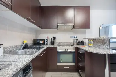 a kitchen with brown cabinets and a sink at StayShort - Extravagant Studio in DIFC with Skyline Views in Dubai