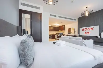 a bedroom with a white bed with a book me sign on the wall at StayShort - Extravagant Studio in DIFC with Skyline Views in Dubai