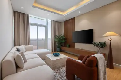 a living room with two white couches and a flat screen tv at Maison Privee - Chic Downtown Living with Dubai Cityscape Views in Dubai