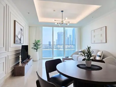 a living room with a table and a television at Venduras- 2BR Retreat , Beach Access , Emaar Beachfront in Dubai