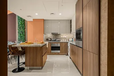 a kitchen with wooden cabinets and a large island at Downtown Luxury 2 Bedroom Apartment with Iconic Burj Khalifa Views, Rooftop Pool, Movie Room, Squash Court, and Kids Club in Dubai