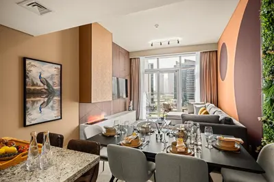 a dining room with a table and chairs and a living room at Downtown Luxury 2 Bedroom Apartment with Iconic Burj Khalifa Views, Rooftop Pool, Movie Room, Squash Court, and Kids Club in Dubai