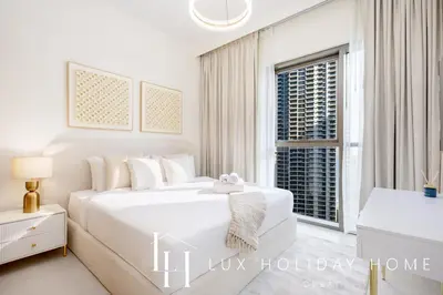 a white bedroom with a large bed and a window at LUX The Creekside Skyline View Suite in Dubai