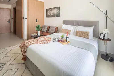 a large white bed with a bottle of wine on it at Frank Porter - Binghatti Azure in Dubai