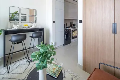 a kitchen with a table and two stools in a room at Frank Porter - Binghatti Azure in Dubai
