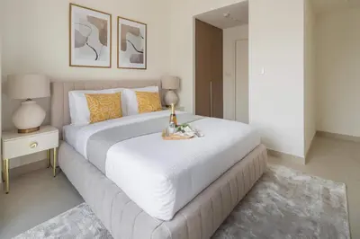 a bedroom with a large white bed with a table at Frank Porter - Lotus at Creek Beach in Dubai
