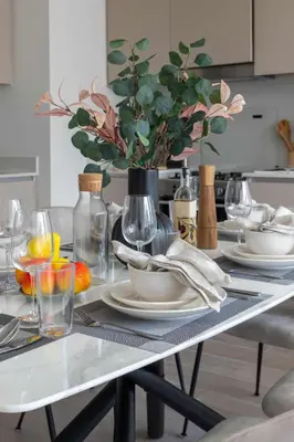 a table with plates and glasses and a vase with flowers at Frank Porter - Lotus at Creek Beach in Dubai