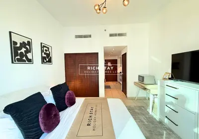 a bedroom with a bed with purple pillows and a television at Boulevard Charm- Studio Hideaway in Dubai
