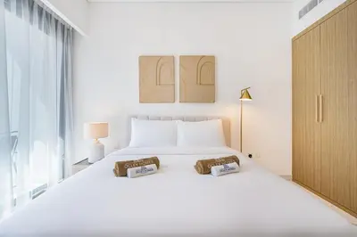 a white bedroom with a large white bed with two pillows at Elegant & Cozy Home with Stylish Modern Interiors in Dubai