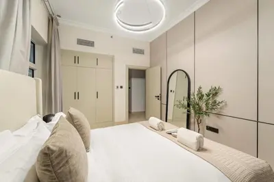 a bedroom with a white bed and a mirror at FIRST CLASS 1BR Canal Views , Gem of Mayfair in Dubai