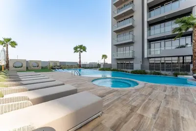 a building with a swimming pool next to a building at 1BDR with Gym, Sauna, Pool - Opposite Circle Mall in Dubai