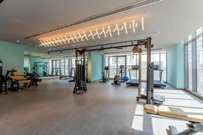 a gym with several treadmills and machines in a room at 1BDR with Gym, Sauna, Pool - Opposite Circle Mall in Dubai