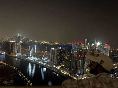 a man standing on a ledge looking at a city at night at Elegant Urban Escape in Dubai