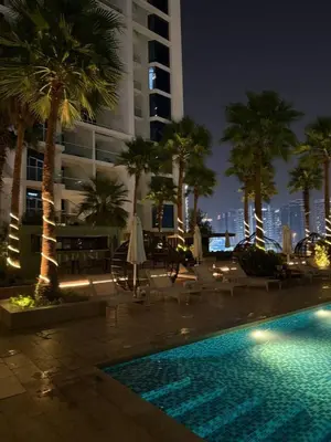 a swimming pool with palm trees and a building at Bright And Spacious Canal View Appartment in Dubai