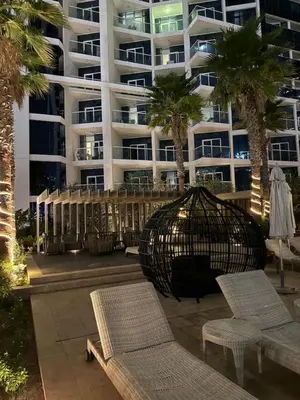 a large apartment building with palm trees in front of it at Studio With Canal View in Dubai