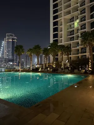 a swimming pool with palm trees and a tall building at Studio With Canal View in Dubai