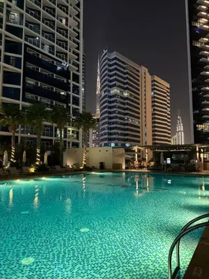 a large swimming pool in a city at night at Bay Luxe Studio in Dubai