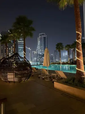 a pool with palm trees and a city skyline at night at Bay Luxe Studio in Dubai