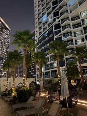 a large building with palm trees and chairs and umbrellas at Bay Luxe Studio in Dubai