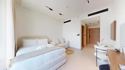 a white bedroom with a large bed and a desk at Vacationer l Bright, Modern Studio Retreat l Free Gym, Pool Access in Dubai