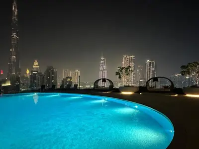 a large swimming pool with a city skyline at night at IMPERIAL AVENUE Brand New Ultra Luxury Full Downtown, Old Town & Burj Khalifa Amazing View! Unforgettable Stay! in Dubai