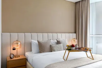a bedroom with a large white bed and a table at Maison Privee - Dazzling Downtown Retreat with Panoramic City Views in Dubai