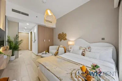 a bedroom with a large white bed and a living room at Newly Listed Airy Boho Studio Azizi Riviera 26 in Dubai