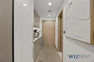 a hallway with a kitchen and a door to a room at Newly Listed Airy Boho Studio Azizi Riviera 26 in Dubai