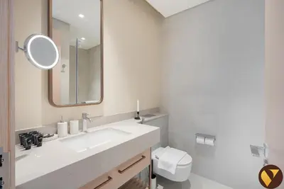 a bathroom with a sink and a mirror and a toilet at Vogue Downtown Vida Dubai Mall, Direct Access to Dubai Mall via Climate Controlled bridge, Two Bedroom Apartment with Full Burj Khalifa View from Balcony and Access to all Amenities in Dubai