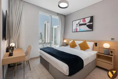 a hotel room with a bed and a desk and a window at Vogue Downtown Vida Dubai Mall, Direct Access to Dubai Mall via Climate Controlled bridge, Two Bedroom Apartment with Full Burj Khalifa View from Balcony and Access to all Amenities in Dubai