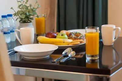 a breakfast table with a plate of fruit and orange juice at DAMAC Maison Cour Jardin in Dubai
