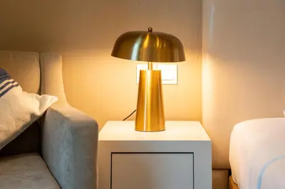 a gold lamp on a table next to a bed at DAMAC Maison Cour Jardin in Dubai