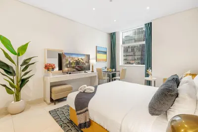 a bedroom with a white bed and a tv at DAMAC Maison Cour Jardin in Dubai