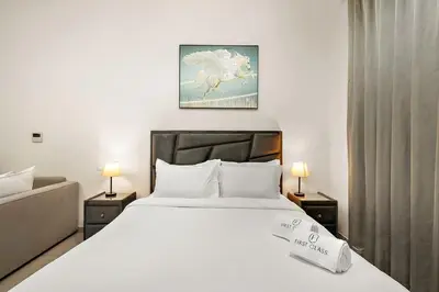 a bedroom with a large white bed with two lamps at FIRST CLASS High End Studio near Miracle Garden in Dubai