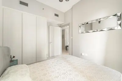 a white bedroom with a large bed and white cabinets at Stylish 1BR w/ Pool View | Heart of Business Bay in Dubai