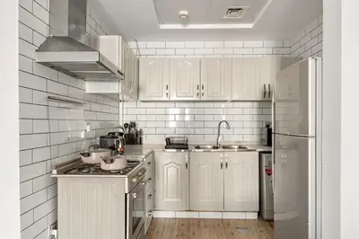 a kitchen with white cabinets and a stainless steel refrigerator at FIRST CLASS 1BR Stylish Escape , Near Metro in Dubai