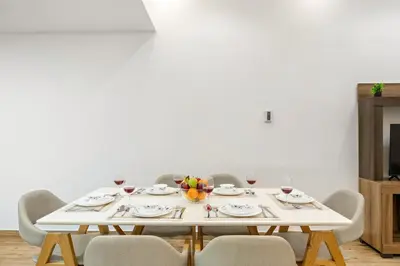a white table with chairs and a white wall at FIRST CLASS 1BR Stylish Escape , Near Metro in Dubai