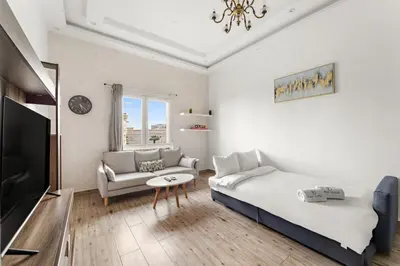 a white living room with a bed and a couch at FIRST CLASS 1BR Stylish Escape , Near Metro in Dubai