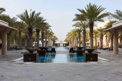 a courtyard with palm trees and chairs and a fountain at Elegant 2BR Beach Apartment Grandeur Residence, Palm Jumeirah in Dubai