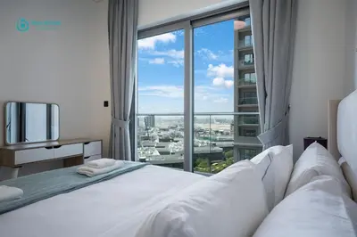 a bedroom with a white bed with a large window at Blue Breeze - Luxury 2BR in Sobha Creek Vistas Near Downtown in Dubai