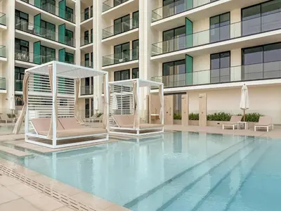 a swimming pool with two chairs and a building at FIRST CLASS 1BR Luxurious JVC Blissful Escape in Dubai