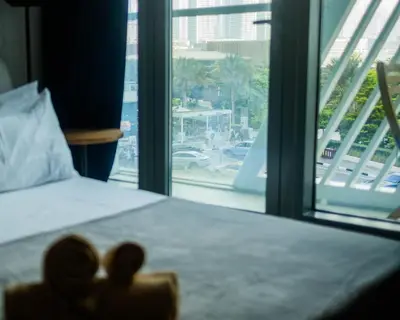a teddy bear sitting on a bed in front of a window at Chic Studio with Beach & Rooftop Pool Access in Dubai
