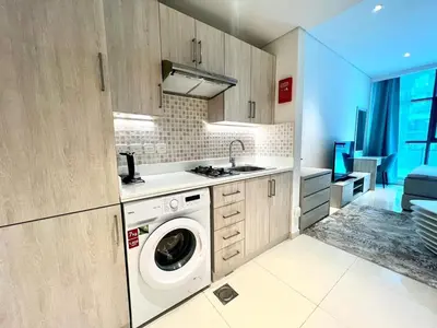 a kitchen with a washing machine and a sink at Chic Studio with Beach & Rooftop Pool Access in Dubai