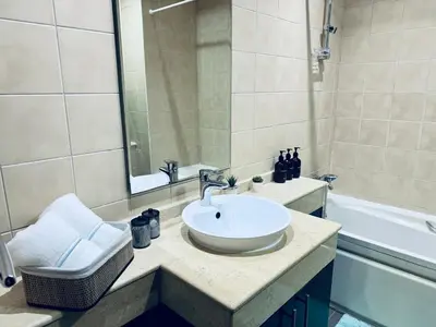 a bathroom with a white sink and a bath tub at COZY 1BD in Dubai Marina in Dubai