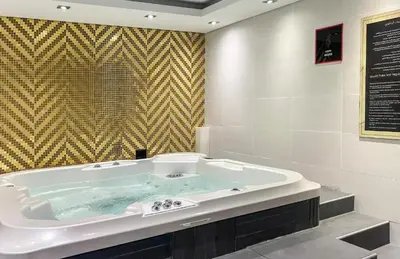 a large bath tub in a bathroom with a wall at Elegant Business Bay 2 Bedroom with Sauna, Pool and Jacuzzi in Dubai