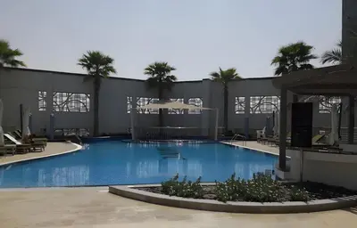 a large swimming pool with palm trees in front of a building at Elegant Business Bay 2 Bedroom with Sauna, Pool and Jacuzzi in Dubai