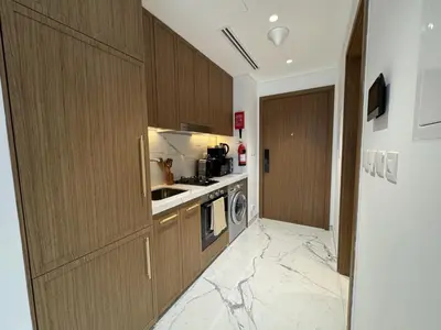 a kitchen with a marble floor and wooden cabinets at DiSalvo Luxury Studio in Azizi riviera 67 in Dubai