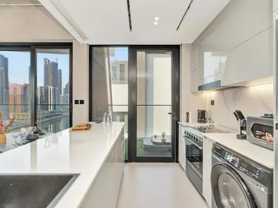a kitchen with white countertops and glass windows at Binghatti Canal 2 Bedroom Suite with Burj Khalifa View, Spacious Balcony, and Infinity Pool in Dubai