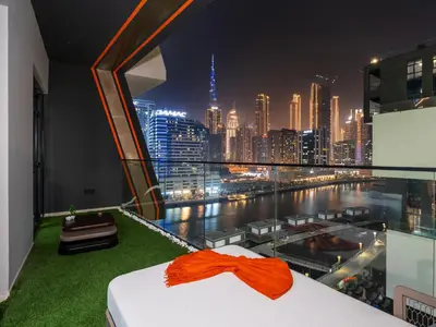 a bedroom with a view of a city at night at Binghatti Canal 2 Bedroom Suite with Burj Khalifa View, Spacious Balcony, and Infinity Pool in Dubai