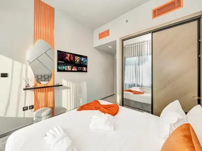 a bedroom with a white bed and a tv at Binghatti Canal 2 Bedroom Suite with Burj Khalifa View, Spacious Balcony, and Infinity Pool in Dubai